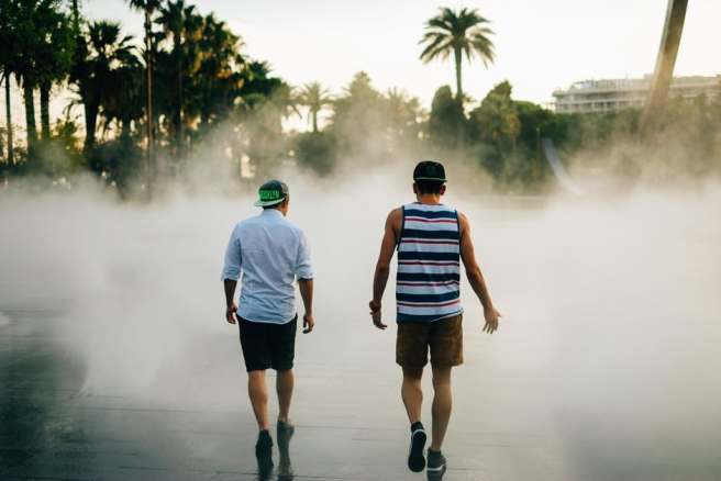 two men walking by a beach on the board walk on a foggy day