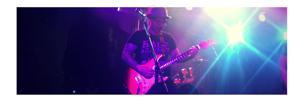 Sal Guzzo plays electric guitar on stage at a BIST 3rd party fundraiier in 2016