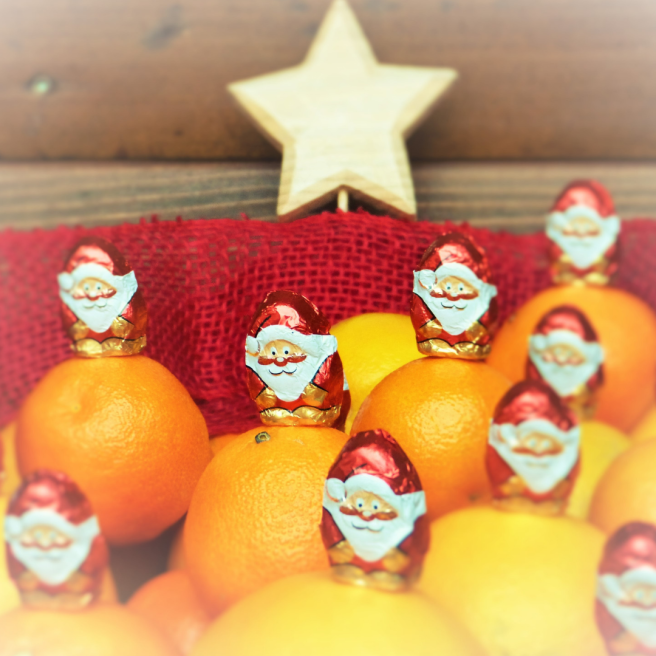 A bowl of chocolate Santas with oranges