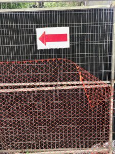 a metal fence with a sign of a red arrow on it